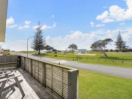 A deck view of a playground and road at Waihi Beach Holiday Home in Waihi Beach