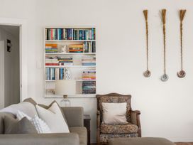 A living room with a bookshelf and armchair at Waihi Beach Holiday Home, Waihi Beach
