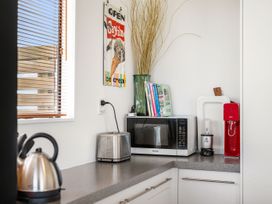 A kitchen with appliances including a kettle and microwave at Waihi Beach Holiday Home in Waihi Beach