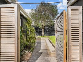 An outdoor pathway between gates and plants at Waihi Beach Holiday Home in Waihi Beach