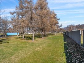 A grassy area with trees and a fence at Antimony Retreat - Cromwell