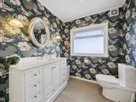 A bathroom featuring a vanity with a sink, mirror, toilet, and floral wallpaper at 