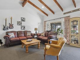 A living room with sofas, a table, and guitars on the wall at The Old Barn in Manchester