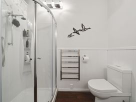 A bathroom featuring a shower, toilet, and towel rack