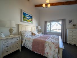 A bedroom with a bed and bedside table at Fisherman’s Cottage - Waikanae Beach