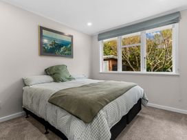 A bedroom with a bed and window at Taotahi Hideaway - Ruakaka