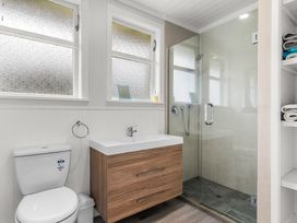 A bathroom featuring a toilet, sink, shower, and window at Taotahi Hideaway - Ruakaka
