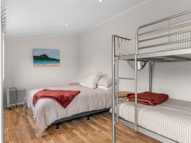 A bedroom with a bed and bunk bed at Taotahi Hideaway - Ruakaka