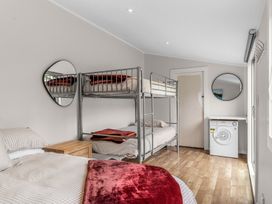 A bedroom with bunk bed and single bed at Taotahi Hideaway - Ruakaka Holiday Home Ruakaka