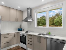 A kitchen with cabinets, stove, sink, and window at Taotahi Hideaway - Ruakaka