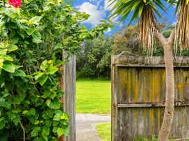 A view through a gate to a grassy area at Taotahi Hideaway - Ruakaka Holiday Home