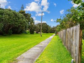 A pathway alongside a fence with trees in a public area at Taotahi Hideaway - Ruakaka
