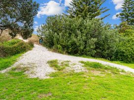 A sand path surrounded by grass and bushes at Taotahi Hideaway - Ruakaka