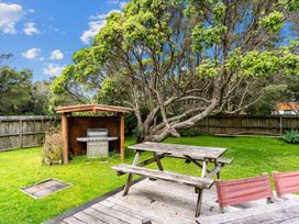 A garden with a grill and a picnic table at Taotahi Hideaway - Ruakaka Waterfront Ruakaka