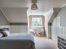 A bedroom with a bed and chairs near a window at Dunluce Coastal Farmstay - Kaikoura