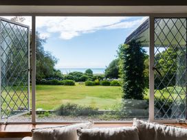 A view from a living room window showing a garden and ocean at Dunluce Coastal Farmstay - Kaikoura Holiday Home Kaikoura