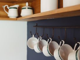 A kitchen with mugs and a cream jug on a shelf at The Shearers Quarters Clarence Farmstay, Kaikoura