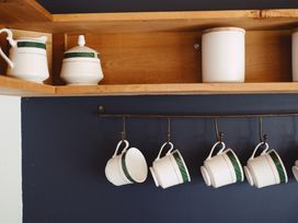 A kitchen shelf with mugs and containers at The Shearers Quarters Clarence Farmstay in Kaikoura