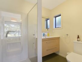 A bathroom with a shower, toilet, sink, and mirror at Koraha Serenity - Linkwater Holiday Home, Marlborough