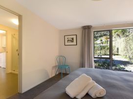 A bedroom with a bed, towels, and a chair at Koraha Serenity - Linkwater Holiday Home, Marlborough
