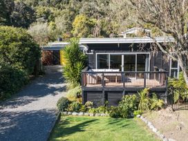 A house with a deck and pathway surrounded by plants at Koraha Serenity - Linkwater Holiday Home Marlborough