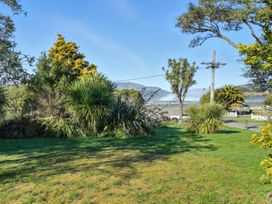 An outdoor view with trees and water in the distance at Maison Pierre Rouge - Duvauchelle Holiday Home Akaroa