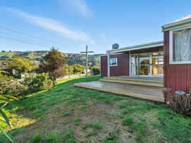 An outdoor area with a deck and grass at Maison Pierre Rouge - Duvauchelle Holiday Home in Akaroa