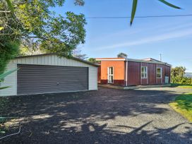A garage and house in the outdoor area at Maison Pierre Rouge - Duvauchelle Holiday Home Akaroa