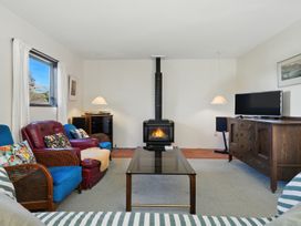 A living room with fireplace and television at Maison Pierre Rouge - Duvauchelle Holiday Home, Akaroa