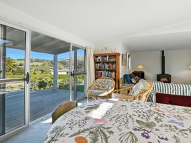 A living room with a sliding glass door and a bookshelf at Maison Pierre Rouge - Duvauchelle Holiday Home, Akaroa