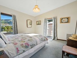 A bedroom with a bed and window at Maison Pierre Rouge - Duvauchelle Holiday Home in Akaroa