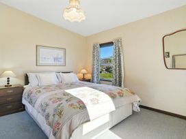 A bedroom with a bed and bedside lamps at Maison Pierre Rouge - Duvauchelle Holiday Home Akaroa