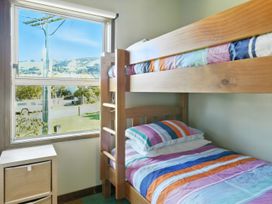 A bedroom with a bunk bed and a nightstand at Maison Pierre Rouge - Duvauchelle Holiday Home Akaroa