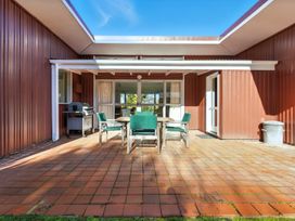 An outdoor patio with a table and chairs at Maison Pierre Rouge - Duvauchelle Holiday Home Akaroa