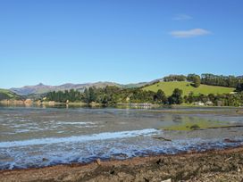 A view of a coastline with water and trees at Maison Pierre Rouge - Duvauchelle Holiday Home Akaroa