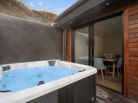 A hot tub next to an indoor dining area at Remarkable QT - Queenstown Holiday Home Queenstown