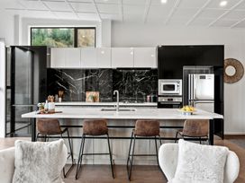 A kitchen with a central island and bar stools at Remarkable QT - Queenstown Holiday Home, Queenstown