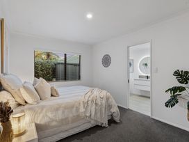 A bedroom with a bed and a door leading to a bathroom at JB's Sanctuary - Papamoa Holiday Home in Papamoa
