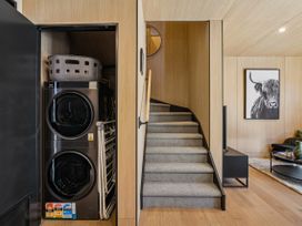 A laundry area with washing machine and dryer in a new home at Pinnacle Peaks - Queenstown Holiday Home, Queenstown
