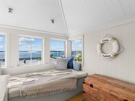 A sunroom with windows, cushions, and a life preserver at Oli Kai - Algies Bay Holiday Home in Algies Bay
