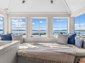 A sunroom with large windows and a cushioned bench at Oli Kai - Algies Bay Holiday Home in Algies Bay