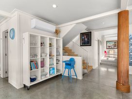 A hallway with a bookshelf and blue chair at Oli Kai - Algies Bay Holiday Home, Algies Bay