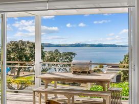 An outdoor deck with a table and grill overlooking the water at Oli Kai - Algies Bay Holiday Home, Algies Bay