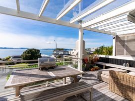 An outdoor patio with a grill and seating at Oli Kai - Algies Bay Holiday Home in Algies Bay