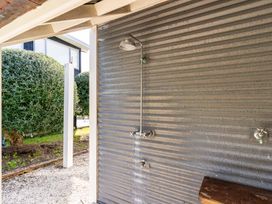 An outdoor shower with a corrugated wall at Oli Kai - Algies Bay Holiday Home in Algies Bay