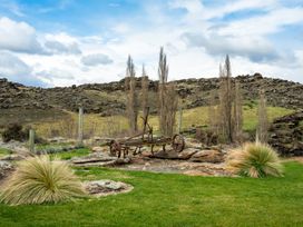 A rusty cart on grass with trees and rocks at an outdoor location