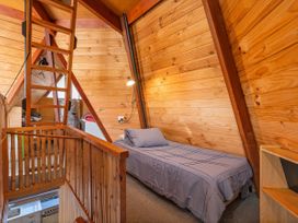 A loft with wooden walls, a bed, and a ladder at the property in 