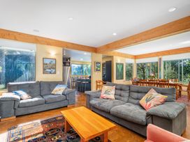 A living room with a sofa, coffee table, and dining area at the property in Whitianga