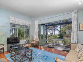A living room with a television and sliding door at The Old Barn in Whitianga