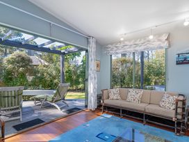 A snug with a sofa and green chairs at The Old Barn in Whitianga